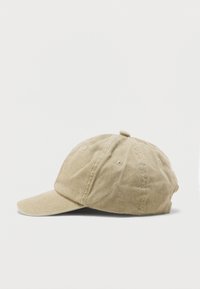 Μπεζ βαμβακερό καπέλο μπάσκετ με ραμμένες επιφάνειες και οπές αερισμού, απεικονιζόμενο από το πλάι σε απλό λευκό φόντο.