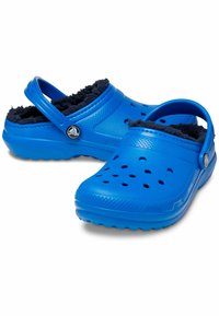 Blaue Clogs mit einer strukturierten Oberfläche, Fleece-Futter und Belüftungslöchern. Mit einem verstellbaren Fersenriemen und einem Logo-Akzent.