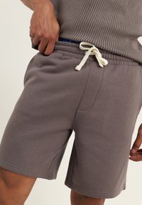 Gray athletic shorts made of soft fabric, featuring an elastic waistband with a white drawstring and side pockets.