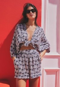 Sada s květinovým potiskem obsahující uzlový crop top s dlouhými rukávy a šortky s vysokým pasem. Barvy: námořnická modrá na bílé s elastickým pasem.