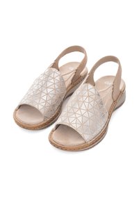 Beige sandals with geometric silver accents, open toe, slingback design, and a textured sole. Cushioned interior for comfort.