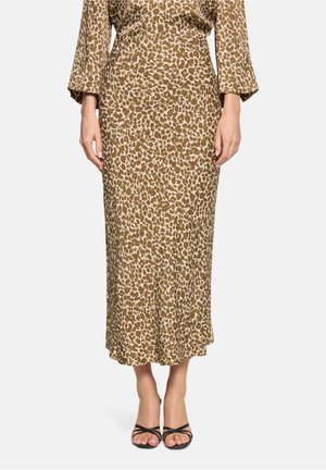 Brauner und beiger Leopardenmuster-Midirock, getragen mit passendem langärmligem Oberteil und schwarzen, offenen Sandaletten mit Riemchen vor einfachem Hintergrund.