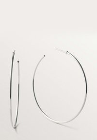 Pendientes de aro grandes y finos de plata, con un acabado liso y cierres de poste, exhibidos sobre un fondo claro y liso.