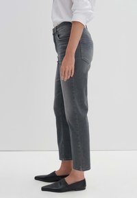 Jeans de mezclilla gris con corte recto, que presentan una cintura de altura media, cinco bolsillos y un acabado ligeramente deslavado. Combinados con zapatos planos negros.