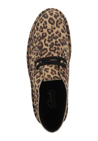 Bota de desierto con estampado de leopardo, hecha de material de gamuza, con patrones marrones y negros, y cordones negros. Textura suave con diseño de punta redondeada.