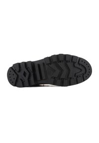 Suela de zapato de goma negra con un patrón de relieve profundo, que presenta surcos angulares y perforaciones circulares para una mayor tracción y durabilidad.