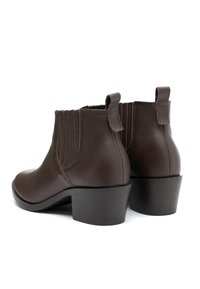 Ciemnobrązowe skórzane botki za kostkę z elastycznymi panelami bocznymi, uchwytami i niskim, warstwowym obcasem, przedstawione z tyłu i z boku.