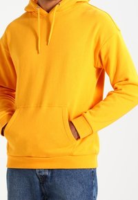 Felpa gialla brillante realizzata in tessuto morbido, con tasca a marsupio, cappuccio regolabile con cordino e polsini e orlo a costine.