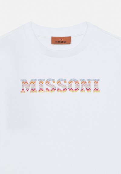 Λευκό T-shirt με λαιμόκοψη και πολύχρωμο ζιγκ-ζαγκ μοτίβο με το κείμενο "MISSONI" στο στήθος και καφέ ετικέτα με το λογότυπο μέσα στον γιακά.