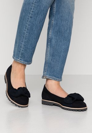 Czarne zamszowe baletki z teksturowaną kokardą na palcu, lekką gumową podeszwą z rowkowanym wzorem oraz niskim profilem.