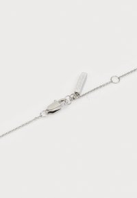 Bracciale in catena d'argento con chiusura a moschettone, etichetta del marchio incisa, collegamenti delicati e design minimalista.