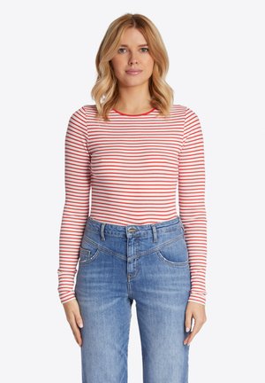 Rot und weiß gestreiftes Langarmshirt mit einem Rundhalsausschnitt, kombiniert mit blauen Jeans aus Denim, die über Vorderseitentaschen und einen taillierten Bund verfügen.