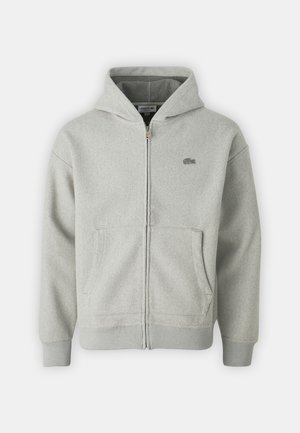 Lichtgrijze zip-up hoodie met steekzakken aan de voorkant, geribbelde manchetten en zoom, en een klein geborduurd logo op de linkerborst.