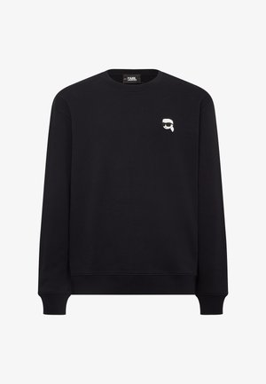 Fekete, kerek nyakú, pamut pulóver, bal mellkason egy napszemüveget viselő arc kis grafikájával. Ribbeszett mandzsetták és alj.