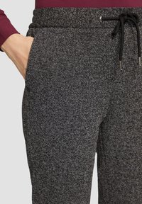 Jogging en chevrons gris avec une taille élastique, cordon de serrage et poches latérales, présentant une finition en tissu texturé.