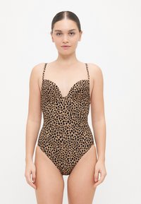 Maillot de bain imprimé animal avec des tons noirs et bruns. Dispose d'un décolleté plongeant, de bretelles fines réglables et d'une coupe ajustée.