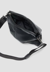 Schwarze Ledertasche mit einem Reißverschluss, strukturierten Oberfläche und verstellbarem Nylonriemen, mit einem kompakten Design und minimalistischer Form.