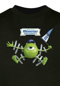 Sort t-shirt med en grøn tegneseriefigur med ét øje, iført en blå cap og omgivet af gråt bånd, med et flag der står "Monsters University."