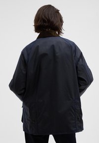 Ναυτικό αδιάβροχο μπουφάν με γιακά από κοτλέ, χαλαρή εφαρμογή και πλαϊνές τσέπες. Λείος υφή με απλό, υπερμεγέθη σχέδιο.