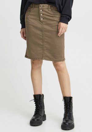Jupe crayon en denim kaki avec fermeture à cinq boutons à l'avant, détails de couture et silhouette droite, associée à des bottes de combat noires à lacets.