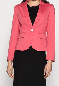 Lyserød skrædderjakke med enkelt knaplukning, notched lapels og to frontlommer. Glat tekstur, tætsiddende design og struktureret form.