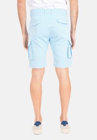 Shorts cargo in cotone azzurro chiaro con tasche laterali, una vita piatta e un design casual, abbinati a sneaker chiare.