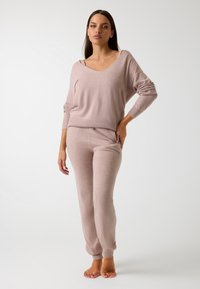 Conjunto de loungewear de punto suave y de color rosa claro que incluye un suéter extragrande de cuello en V con puños acanalados y pantalones ajustados a juego con una cintura elástica.