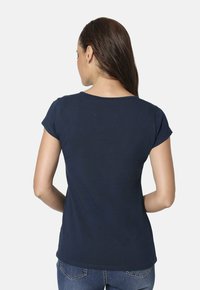 Camiseta de manga corta en azul marino con cuello redondo. Tejido de algodón suave, diseño ajustado y detalles en las costuras laterales. Sin gráficos visibles.