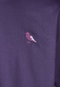 Lila Baumwoll-T-Shirt mit einem gestickten pinken Vogelmotiv auf der Vorderseite. Der Stoff hat eine glatte Textur und einen klassischen Rundhalsausschnitt.