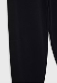 Zwarte broek met een zachte textuur, voorzien van een zijzak en een gestroomlijnd ontwerp. De stof lijkt elastisch en comfortabel.