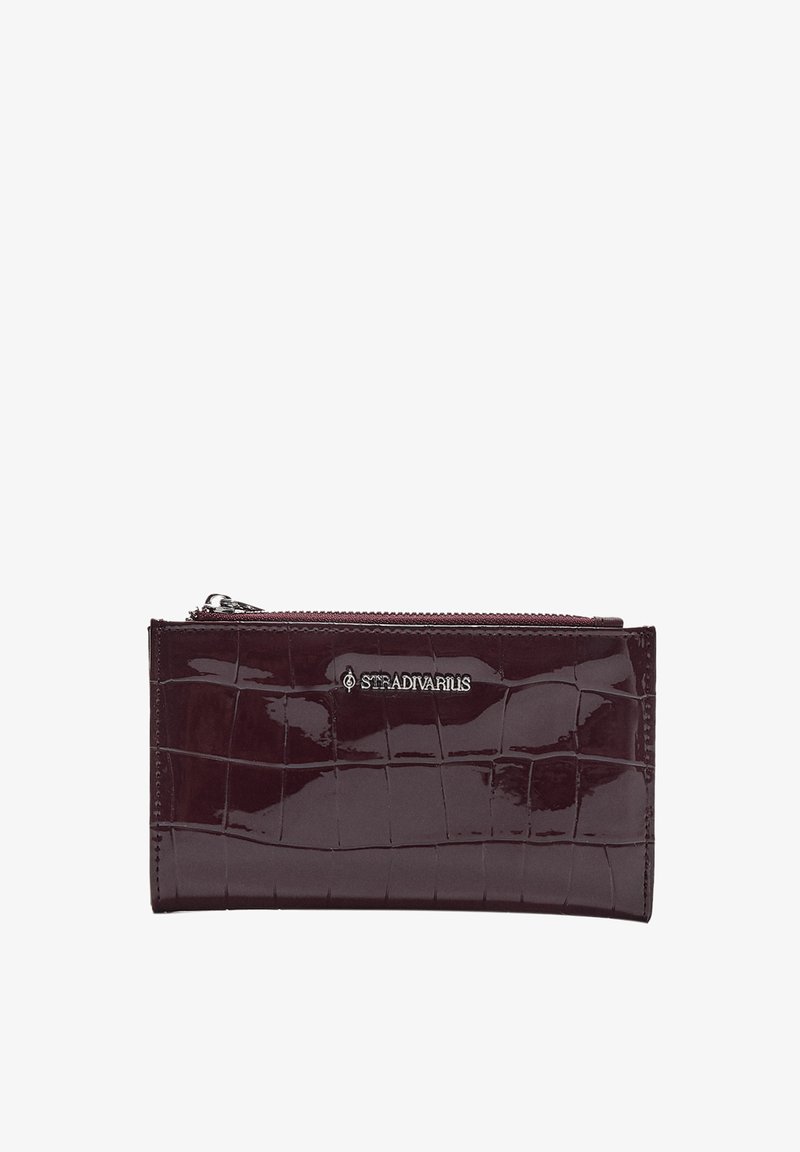 Glossy burgundy faux leather wallet with crocodile pattern, featuring a top zipper and a silver logo. Compact rectangular shape.