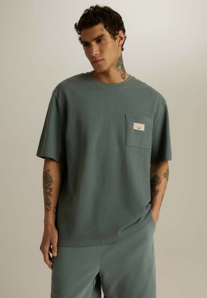 T-shirt z krótkim rękawem, luźny krój w stonowanej zieleni, wykonany z teksturowanej tkaniny, z kieszonką na piersi z metką.