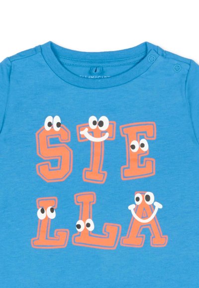 Maglietta blu con lettere arancioni che formano la scritta "STELLA", ogni lettera ha occhi da cartone animato e alcune hanno bocche sorridenti.