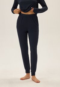 Granatowy zestaw odzieży domowej składający się z długiego rękawa i zwężanych spodni, wykonany z miękkiego materiału z elastycznym pasem i dopasowanymi mankietami.