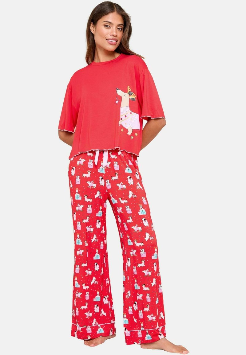 Cămașă de pijama roșie cu mânecă scurtă, decorată cu un grafic de ren, asortată cu pantaloni roșii, cu un model care include cadouri și animale. Material moale, croială lejeră.