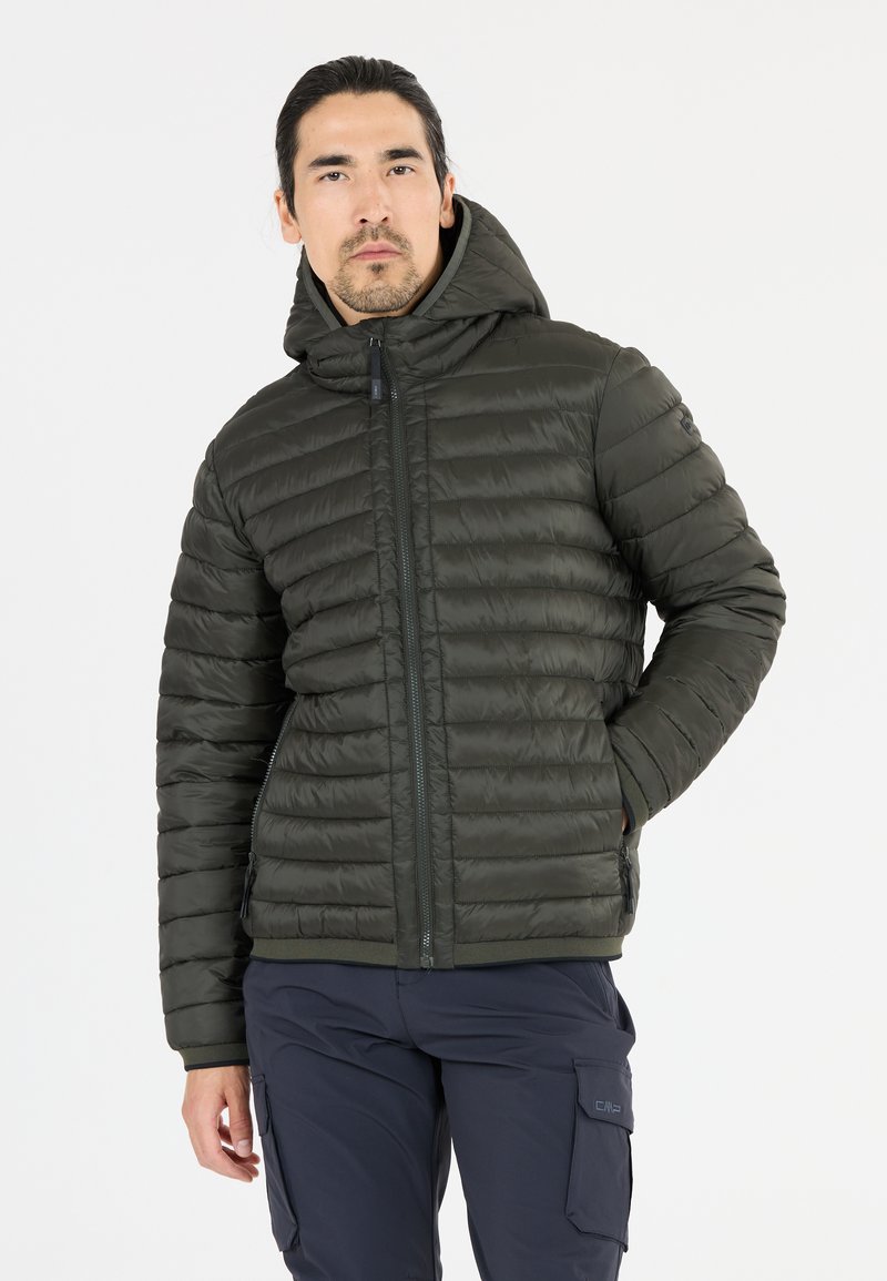 Olivgrön puffjacka med huva, quiltad textur, framzipper och ribbade ärmslut. Kombinerad med marinblå cargobyxor.