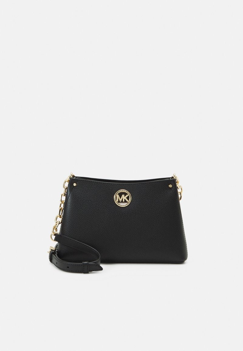 Bolso cruzado de cuero negro con un acabado mate, logo dorado de MK y una correa con detalles de cadena. Presenta una forma rectangular y cierre de cremallera.