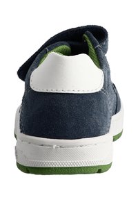 Blauer Wildlederschuh mit weißem Absatz und grünen Akzenten. Verfügt über einen Klettverschluss und eine profilierte Sohle für besseren Halt. Sauberes, sportliches Design.