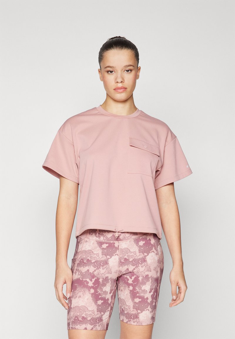 Svetle růžový krátký rukáv crop top s detailním předním kapsou. V kombinaci s šortkami do kolen s vzorem v růžových a mauve tónech.