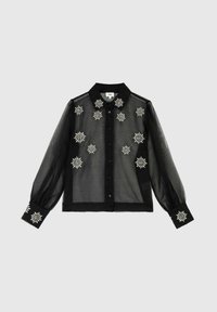 Blouse noire transparente avec de longues manches bouffantes, un col, une fermeture à boutons à l'avant et des accents en broderie florale blanche.