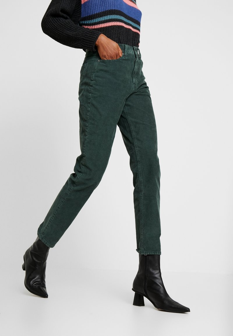 Mörkgrön kordjeans med skräddarsydd passform och rak ben, med hög midja och subtil textur, parat med svarta ankelboots.