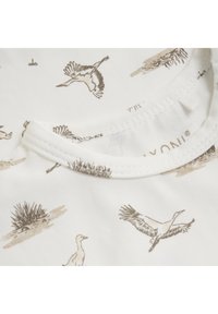 T-shirt en tissu blanc à col rond avec un design imprimé d'oiseaux dans des tons beige et marron. La texture semble douce et lisse.