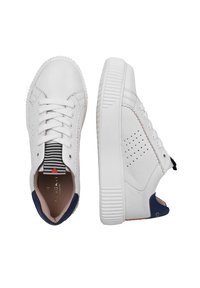 Witte lage sneakers met dikke zolen, veters aan de voorkant, marineblauwe hielaccenten en een tongtrekstrook met strepen en een rood hartdetail.