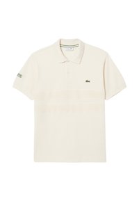 Polo de couleur crème en tissu lisse avec un col à côtes. Présente un logo brodé vert sur la poitrine gauche et la manche.