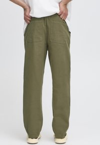 Olive green wide-leg trousers, made from cotton, featuring two back pockets and a relaxed fit. Textured fabric with a smooth finish.