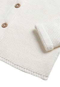 Cardigan lavorato a maglia di colore crema, con un motivo a punto testurizzato, bottoni in legno e dettagli con polsini ripiegati.