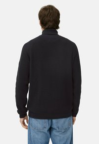 Dunkelblauer, strukturierter Strickpullover mit hohem Kragen, gerippten Bündchen und Saum. Er hat eine lockere Passform und kaum Details auf der Rückseite.