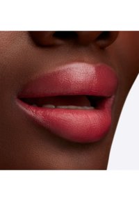 Gros plan sur des lèvres avec une finition rose mat, mettant en valeur une texture lisse et un éclat subtil sur une peau foncée.