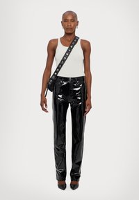Zwarte lakleren broek met een hoge taille, met een glanzende afwerking, rechte benen en gedetailleerde stiksels. Gepaard met een licht tanktop.