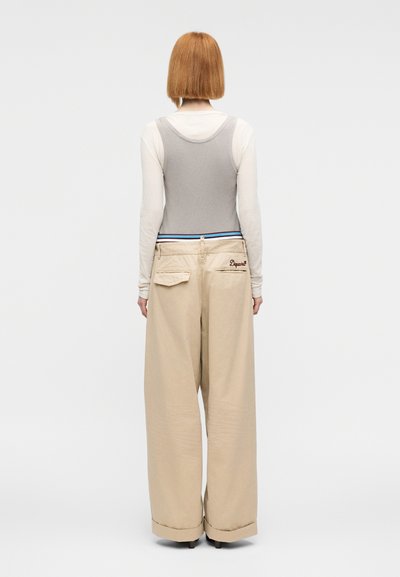 Φαρδιά παντελόνια σε ανοιχτό μπεζ χρώμα με ρυθμιζόμενη μέση με κορδόνι και πίσω τσέπες, συνδυασμένα με γκρι ριπ αμάνικη μπλούζα.